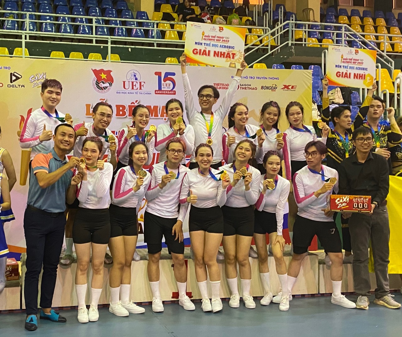 Tiến sĩ Phan Bảo Giang (hàng dưới thứ nhất bên trái) chia sẻ khoảnh khắc vinh quang cùng với đội tuyển Aerobic Khoa Quan hệ Công chúng và Truyền thông khi nhận chiếc Huy chương vàng tại Olympic UEF 2022